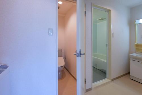 ein Badezimmer mit einem WC und einer Glastür in der Unterkunft Miyazaki Mango Hotel - Vacation STAY 58309v in Miyazaki