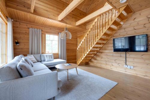 a living room with a couch and a tv and stairs at Lomamökki Himos Taivaanranta in Jämsä