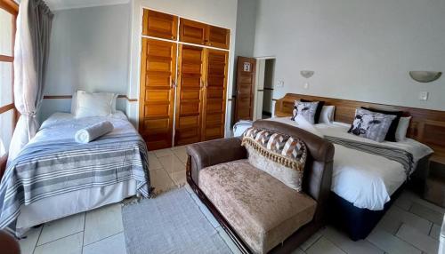 a bedroom with two beds and a couch and a chair at Eagles View Kungwini in Erasmus