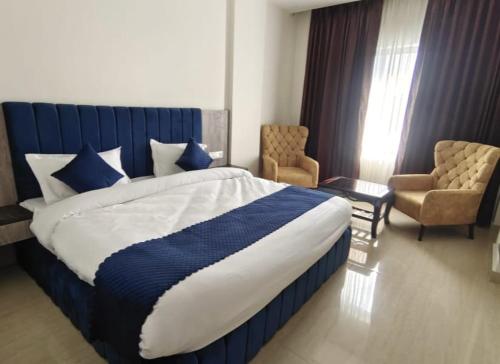 Un dormitorio con una cama azul y blanca y una silla en HOTEL NEW BADRINATH, en Badrīnāth