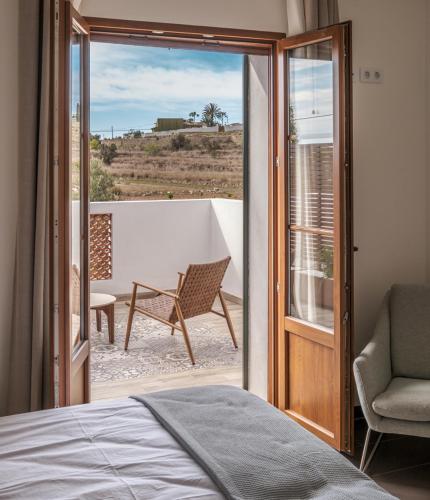 a bedroom with a bed and a balcony with a chair at Finca de la Pansa in Benissa