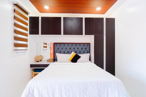 a bedroom with a white bed with a wooden headboard at Q Beach Resort in Cabangan