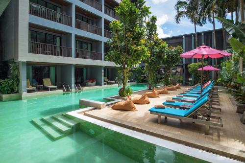 a hotel pool with lounge chairs and umbrellas at Areetara Aonang Krabi in Ao Nang Beach