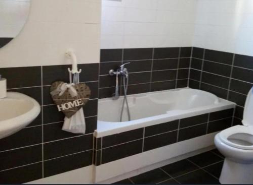 y baño con bañera, aseo y lavamanos. en Beva Hotel, en Sarandë
