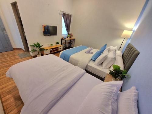 a hotel room with two beds and a television at Zizi Homey Cemara Asri 302 in Pulauberayan Dadap