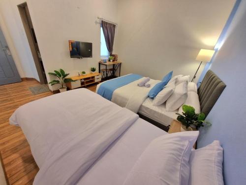 a hotel room with two beds and a television at Zizi Homey 302 Cemara Asri in Pulauberayan Dadap