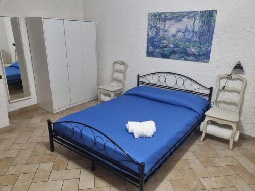 een slaapkamer met een blauw bed en 2 stoelen bij La Casina di Sotto in Castelnuovo di Garfagnana