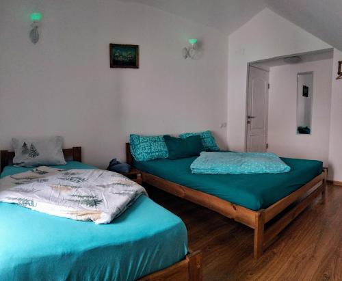 two twin beds in a room with wooden floors at Doi Iepuri in Azuga