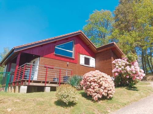 een rood huis met een balkon en een aantal bloemen bij Chalet idéal 4-8 pers avec garage 20 mn Gérardmer in Vienville