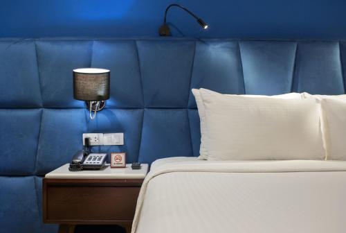 un lit avec une tête de lit bleue et un téléphone sur une table de nuit dans l'établissement Hanoi Brilliant Hotel & Spa, à Hanoï