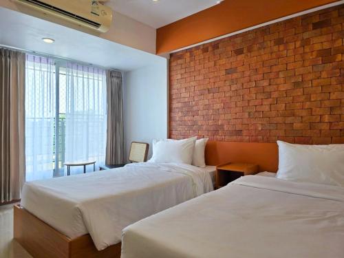 um quarto de hotel com duas camas e uma parede de tijolos em Wangkaew Hotel em Phitsanulok