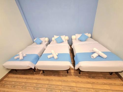 3 camas en una habitación con almohadas azules y blancas en Zizi Homey Cemara Asri Triple Room 202, en Medan