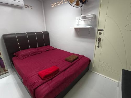 Cama pequeña en habitación pequeña con sábanas rojas en ROOMSTAY NIMAZA Bilik 2, en Marang