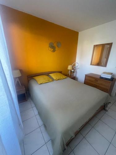 - une chambre avec un grand lit et un mur jaune dans l'établissement Joli appartement avec piscine, à Antibes