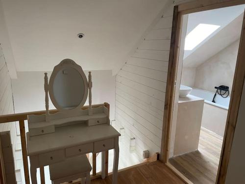 La salle de bains est pourvue d'un lavabo et d'une coiffeuse avec un miroir. dans l'établissement Chalet 6-8 personnes avec jeux et jaccuzi - Nahleo Chalet, à Villers-lès-Pots
