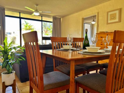 a dining room with a table and chairs with wine glasses at Riverview Holiday Apartment 92 - Kalbarri WA in Kalbarri