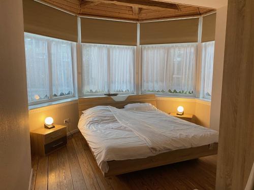 een slaapkamer met een bed met 2 nachtkastjes en 2 ramen bij Seehaus Plön in Plön