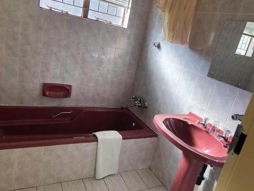 a bathroom with a red tub and a sink at Kamogelo Guest House in Pilanesberg