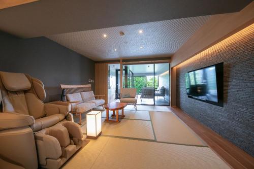 a living room with a couch and chairs and a television at Hotel Higashidate in Yamanouchi