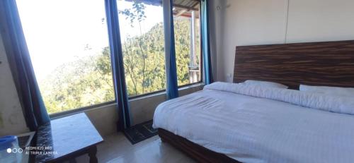 a bedroom with a bed and large windows at Dhanolti Resort in Dhanaulti
