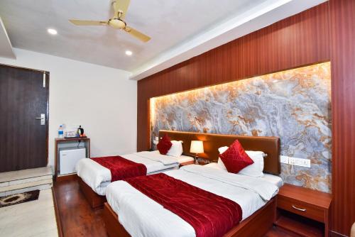 two beds in a hotel room with a painting on the wall at Pinaz Royale in Amritsar