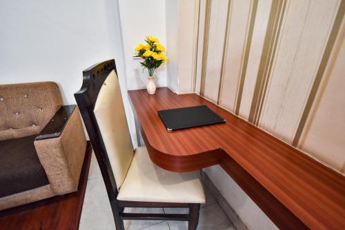 a desk with a vase of yellow flowers on it at Pinaz Royale in Amritsar