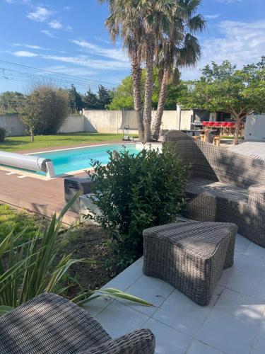 - une piscine avec des chaises en osier dans l'établissement CHARMANT STUDIO INDEPENDANT PROCHE MER parking privé, à Mireval