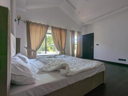 1 dormitorio con 1 cama blanca grande y ventana en Adventure Techie Resort, en Islamabad