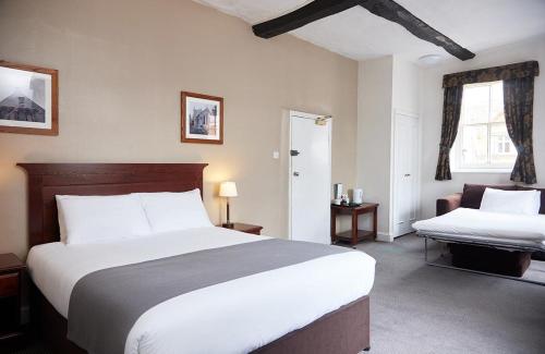 a hotel room with a large bed and a chair at George Hotel by Greene King Inns in Huntingdon