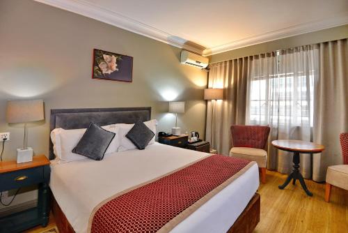 a hotel room with a bed and a chair at Cresta Jameson Hotel in Harare
