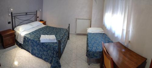 a bedroom with two beds and a desk and a window at Albergo B&B Antica Trattoria Bacco in Circello