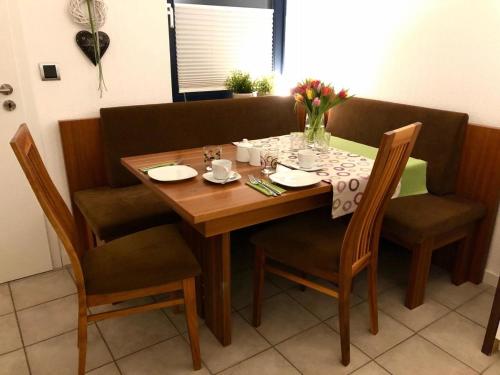 a dining room table with chairs and a wooden table with flowers on it at Ferienwohnung Am Flörbach in Ahaus