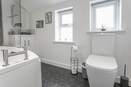 Baño blanco con aseo y lavamanos en Eton House coastal villa with great outside space en Sheringham
