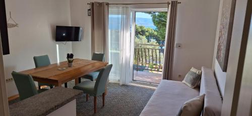 a dining room with a wooden table and a balcony at Summerhouse Duće Omiš in Duće