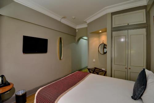 a bedroom with a bed and a tv on the wall at Cresta Jameson Hotel in Harare