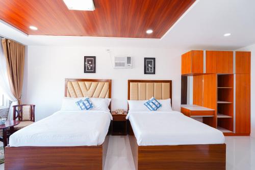 2 camas en una habitación con paredes blancas en Q Beach Resort en Cabangan