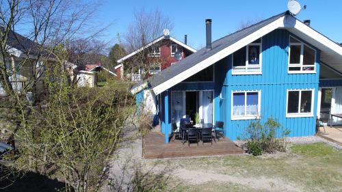 ein blaues Haus mit einem Tisch und Stühlen auf einer Veranda in der Unterkunft Ferienpark - Komfort-Ferienhaus mitten in der Natur 5 Personen #67 in Bremke