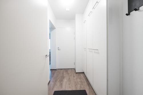 a hallway with white cabinets and a black rug at Forenom Serviced Apartments Helsinki Lastenkodinkuja in Helsinki