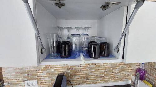 une armoire remplie de vases en verre sur une étagère dans l'établissement Criber House - Casa din Fibra de sticla pe ponton plutitor, à Bicaz