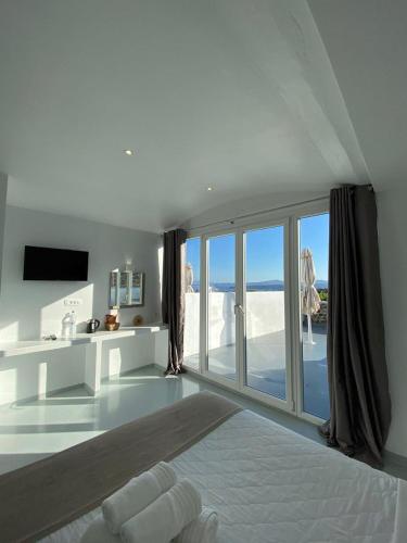 a white room with a bed and a large window at Serenità Luxury Suites in Akrotiri