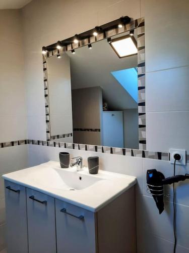 une salle de bain avec un lavabo et un grand miroir dans l'établissement Cap sur l'océan, à Saint-Brévin-les-Pins