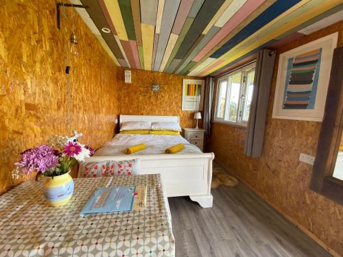 a bedroom with a bed and a table with flowers at Sunrise Cabin in Carbis Bay