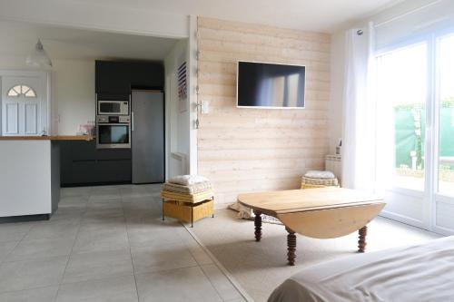 un salon avec une table et une télévision au mur dans l'établissement Maison récente idéalement située aux Sables dOlonne - 4 pers, à Les Sables-dʼOlonne