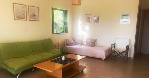 a living room with a green couch and a table at Wave Sound - summer apartment in Kakóvatos