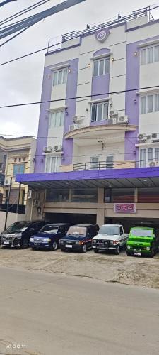 ein lila Gebäude mit davor geparkt in der Unterkunft Erin Int Hotel in Sungguminasa