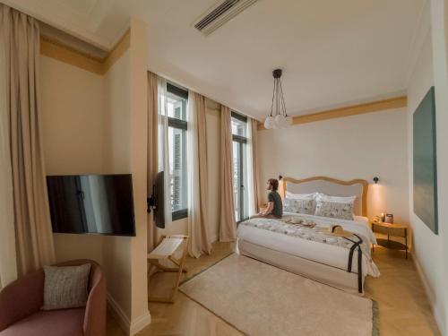 a woman is sitting on a bed in a bedroom at EPICURE SUITES in Kavala