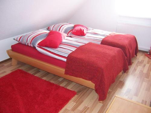 1 cama con 2 almohadas rojas y manta roja en Ferienhaus Waldfee en Reutin