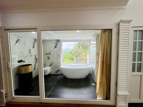 a bathroom with a large tub and a window at HOTEL WHITE HOUSE, Munnar in Munnar