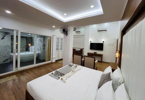 a bedroom with a white bed and a television at HOTEL WHITE HOUSE, Munnar in Munnar