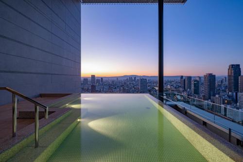 a swimming pool on the roof of a building with a city skyline at Candeo Hotels Osaka The Tower in Osaka